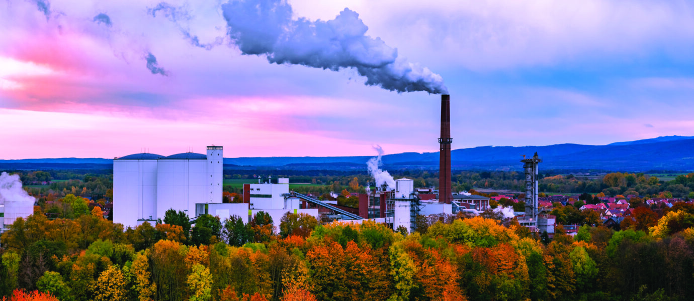 Photo d'une usine avec une cheminée dont de la fumée sort.